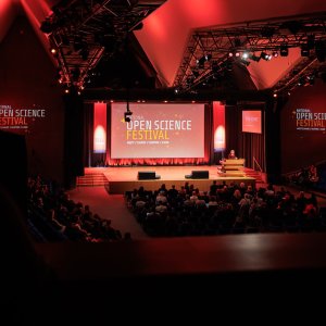Plenary opening session in the TU Delft auditorium, with the OSF logo displayed on the backdrop