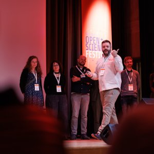 The award winner gives a presentation on stage. Behind the winner stand the five other team members